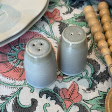 Load image into Gallery viewer, Aquarius Sage stoneware salt and pepper shakers with reactive glaze, on a patterned cloth. 