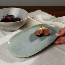 Load image into Gallery viewer, Aquarius Sage stoneware small oval platter with reactive glaze and concentric line pattern, with figs on a linen cloth with matching bowl. 