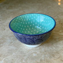 Load image into Gallery viewer, Blue Waves porcelain pinch bowl with blue stamped exterior pattern and rim, teal interior with white geometric pattern, and white pedestal base on a marble surface. 