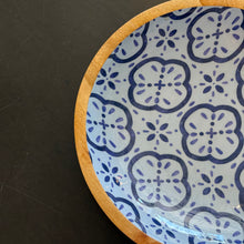 Load image into Gallery viewer, Amalfi Cucina shallow bowl close-up showing blue geometric floral pattern on white interior with mango wood rim against a dark background.  