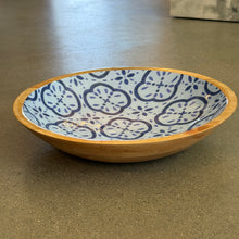 Load image into Gallery viewer, Amalfi Cucina shallow bowl side view with blue geometric floral pattern on white interior and mango wood exterior and rim displayed on a dark surface. 