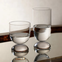 Load image into Gallery viewer, Zodax Madrid glassware featuring a highball and short tumbler with rounded half-dome bases, displayed filled on reflective surface. 