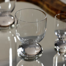 Load image into Gallery viewer, Zodax Madrid short tumbler with rounded half-dome base in clear glass, displayed on reflective surface with other glassware.  