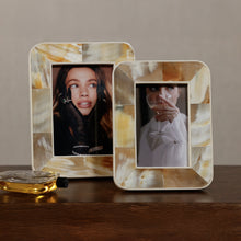 Load image into Gallery viewer, Zodax Dune African white horn photo frames in two sizes with marbled cream, ivory, and amber tones in a geometric inlay, displayed with inset portraits on a wood surface. 