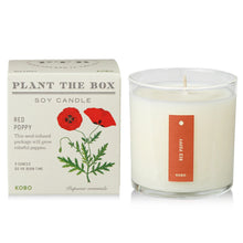 Load image into Gallery viewer, Red Poppy Plant The Box Candle, unlit white wax candle in clear glass jar with red label beside illustrated red poppy plant product box against white background. 