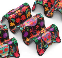 Load image into Gallery viewer, Multi Taco Holder, three curved two-section melamine taco holders with Day of the Dead sugar skulls and floral designs in purple, golden yellow, red, aqua, and pink on black background, displayed on white background. 