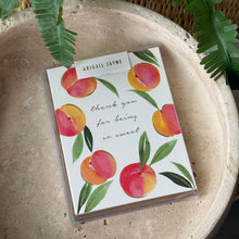 Load image into Gallery viewer, Sweet Peaches Thank You Cards Box Set, hand-painted watercolor-style peach design with gold foil text on white textured felt paper cards in clear packaging box on neutral stone surface with green fern fronds in background. 