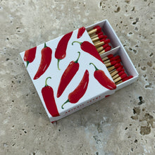 Load image into Gallery viewer, Spicy Peppers Boxed Matches, boxed wooden safety matches with watercolor red pepper design on white sliding cover, red-tipped sticks partially open on neutral stone.