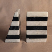 Load image into Gallery viewer, Striped Black &amp; White Marble Bookends, set of hand-shaped, assembled, and polished deep black and white marble triangular wedge-shaped bookends with horizontal striped bands, displayed with one bookend facing forward and the other shown from the side on a beige surface and against a coordinating beige background. 