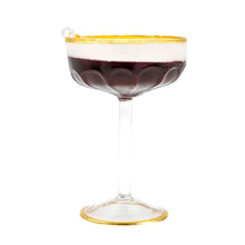 Load image into Gallery viewer, Espresso Martini Ornament, side view of clear coupe ornament with gold rim and matching gold-trimmed base, layered dark brown espresso and white foam, scalloped lower bowl, clear stem, white hanging loop, against a white background. 