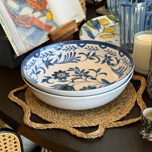Load image into Gallery viewer, Sunshine Placemat, braided seagrass placemat with a scalloped edge, displayed beneath stacked blue and white floral  bowls on dark wood dining table with coordinating blue glassware and table decor. 