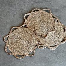 Load image into Gallery viewer, Sunshine Placemat, three overlapping braided seagrass placemats with scalloped outer edges on gray textured surface. 