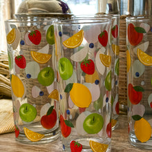 Load image into Gallery viewer, Fresh Picked Drinks Glass Set, close-up view of four clear glass tumblers with colorful fruit illustrations including lemons, strawberries, green apples, blueberries,  and orange slices on a rustic surface. 