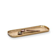 Load image into Gallery viewer, Medium Gold Oval Tray, medium lightweight oval tray with a warm burnished gold finish, raised rim, and rounded corners, shown with gold-tone and rose gold-tone spoons, against a white background. 