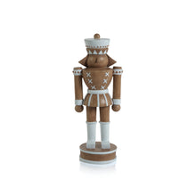 Load image into Gallery viewer, Brown nutcracker figurine with a matte finish and white details, including a round hat, collar, belt, cuffs, and boots with geometric accents. Standing on a brown round base with white stripes. Displayed against a white background. 