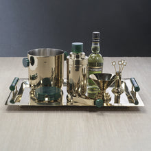 Load image into Gallery viewer, Gold-tone alloy metal bar set on a matching rectangular tray with green resin handles, featuring an ice bucket with green side handles, a cocktail shaker with green lid, a bottle of Chartreuse, a gold funnel-style martini glass, tongs with green handle tips, and gold cocktail picks. All arranged on a light wood surface against a dark background. 