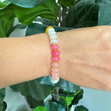 Load image into Gallery viewer, Color Garden Stone Beaded Stretch Bracelet, multicolored natural stone stretch bracelet worn on a wrist, featuring beads in shades of yellow, white, and pink with gold-tone spacer beads, shown against a backdrop of lush green leaves.  