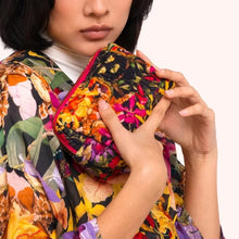Load image into Gallery viewer, Botanical Kaleidoscope Quilted Vanity Bag, model wearing a matching kimono holding compact zippered vanity bag featuring hot pink trim and a vibrant multicolored floral rainforest pattern against a white background. 