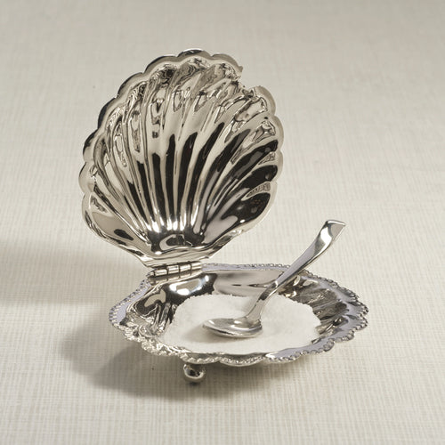 Polished nickel fan shell lidded bowl with matching spoon featuring a scalloped design and beaded rim, displayed open on a light surface with white contents inside the bowl.