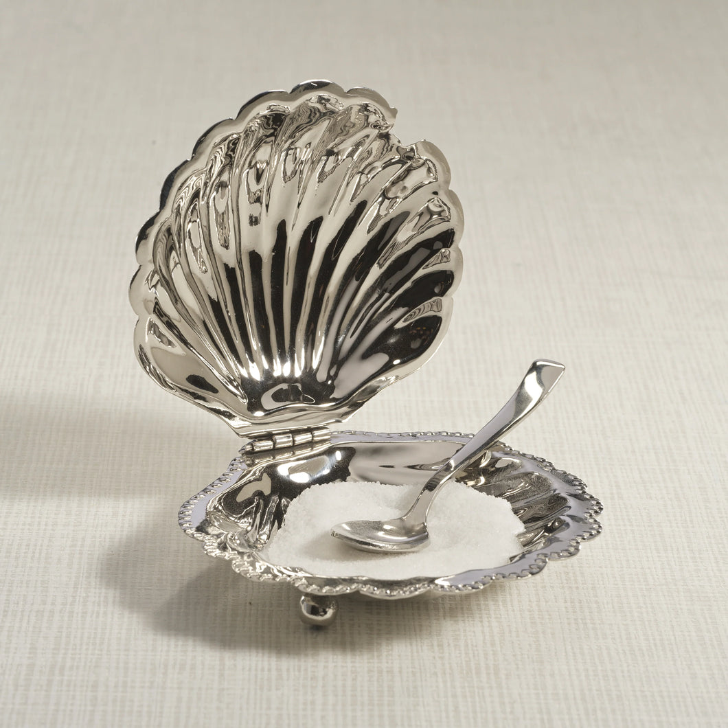 Polished nickel fan shell lidded bowl with matching spoon featuring a scalloped design and beaded rim, displayed open on a light surface with white contents inside the bowl.