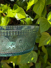 Load image into Gallery viewer, Decorative green glass bowl with embossed patterns on a leafy green background.