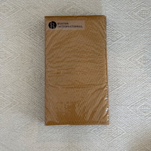Load image into Gallery viewer, Gold Herringbone Textured Guest Towel, overhead view of rectangular gold-colored paper guest towels with a subtle herringbone texture, wrapped in clear packaging with a rectangular white Boston International label in the upper-left corner, resting on cream fabric with a woven geometric pattern.