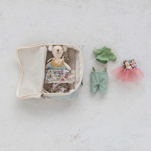 Cream-colored fabric suitcase with floral bedding and pillow, a small plush white bear dressed in a yellow top and blue tulle skirt, shown beside additional outfits including light blue pants, green top, and a floral top with a pink tulle skirt, displayed against a white background.  
