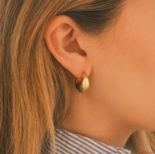 Load image into Gallery viewer, Close-up of an ear wearing a 14k gold semi-matte double plated brass casting hoop earring. Person has blonde hair and a blue and white striped top.