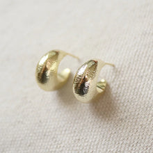 Load image into Gallery viewer, 14K gold semi-matte double plated brass casting hoop earrings with sterling silver posts on a cream woven fabric surface. 