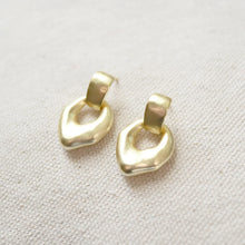 Load image into Gallery viewer, 14K gold semi-matte gold plated brass casting dangle earring with sterling silver post on a cream woven fabric surface.