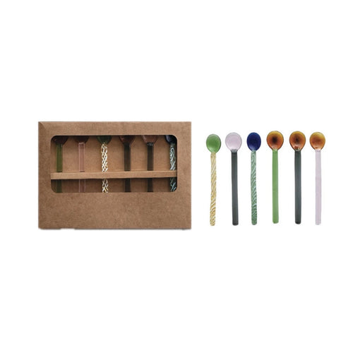 Set of colorful glass spoons with a set of colorful spoons in packaging on a white background. 