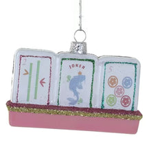 Load image into Gallery viewer, Mahjong Tiles Ornament, front view of three white tile shapes on a pink rack with dusty rose pink and gold glitter trim, featuring a two-bamboo design, a fish illustration beneath “JOKER,” and five colored circles, with glitter borders and a silver-colored cap and hanging cord, against a white background.