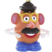 Load image into Gallery viewer, Potato Head Ornament, front view of an orange-brown potato-shaped character with yellow glasses, a black hat, a textured black mustache, glittery pink nose and ears, white arms and gloves, red smiling lips, blue glitter-accented shoes, and a gold-colored ornament cap, against a white background.